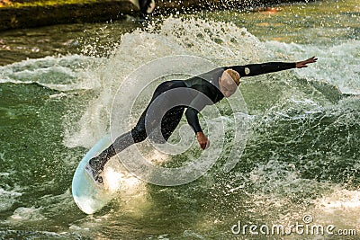 Munich, Germany - July 13, 2021: Surfer in the city river Eisbach. Munich is famous for surfing in urban enviroment Editorial Stock Photo
