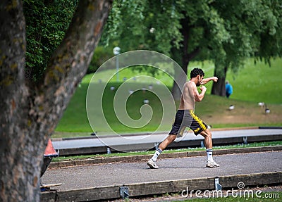 MUNICH, GERMANY - Jun 01, 2020: Strong athletic young man performs boxing exercises in a park Editorial Stock Photo