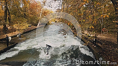 MUNICH, GERMANY, November 18, 2019: Real time wide shot of Urban Surfers on a wave on the Eisbach river. River Surfing Editorial Stock Photo