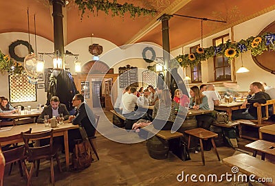 Women and men eating and drinking beer inside traditional restaurant in old Bavarian style Editorial Stock Photo