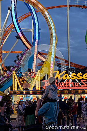 Munich, Germany - September 24: a father is carrying his young son on his shoulders in front of a 5 loop roller coaster on the Editorial Stock Photo