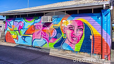 Mural graffiti wall art of a colourful lady with flower in car park area Editorial Stock Photo