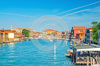 Murano islands water canal with Santa Maria degli Angeli church, boats and motor boats, row of traditional buildings Stock Photo