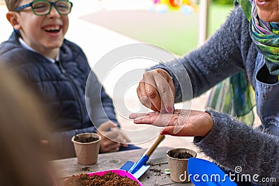 Murcia, Spain, February 5, 2020: Young children learning how to plant seeds in garden. Hands holding seeds and black soil in pot. Editorial Stock Photo