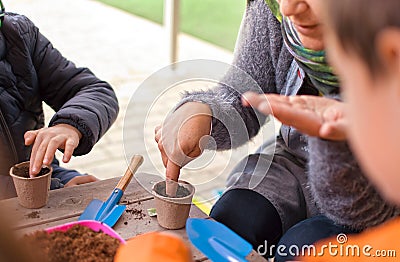 Murcia, Spain, February 5, 2020: Young children learning how to plant seeds in garden. Hands holding seeds and black soil in pot. Editorial Stock Photo