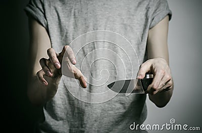 Murder and Halloween theme: a man holding a knife on a gray background Stock Photo