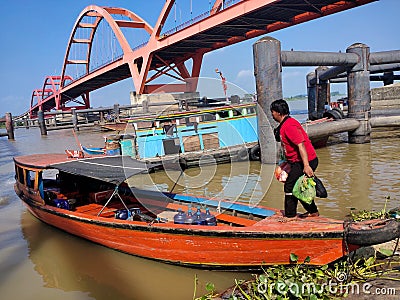 Murky river with bridge, people, boats, plants, trees and blue sky background Editorial Stock Photo