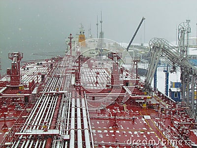 Oil tanker being oil pumped at sea port at winter Editorial Stock Photo