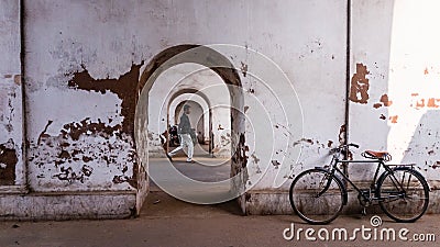 A bicycle parked beside the walls of an old, arched, faded tunnel with diminishing Editorial Stock Photo