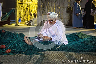 A traditional fisherman is weaving a fishing net at Muscat Festival a fishing net Editorial Stock Photo