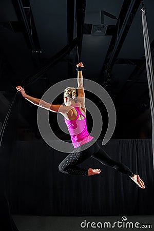 Muscular Aerialist In An Arabesque Pose From a Belay Loop Stock Photo