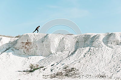 African athlete, silhouette against the sky at sunrise while running in the mountains along a steep path Stock Photo