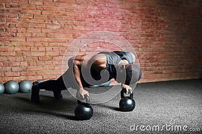 Muscular african man doing push ups against dark background. Stock Photo