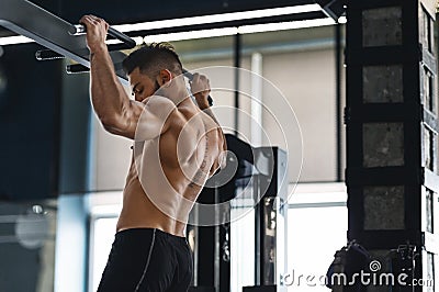 Muscular athlete pulling up on horizontal bar at gym Stock Photo