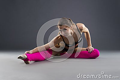 Muscular attractive fitness woman warming up in the studio on gray background Stock Photo