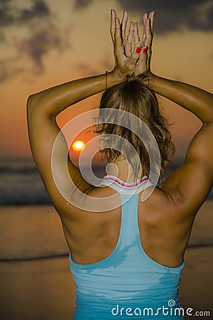 Muscular back of fit and healthy attractive woman practicing fitness and yoga in beautiful sunset beach in meditation and relaxati Stock Photo