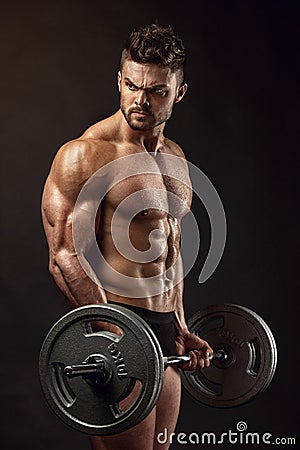 Muscular bodybuilder guy doing exercises with big dumbbell Stock Photo