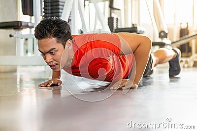 Muscular bodybuilder guy doing push ups exercise in fitness gym . young sport asian man training . workout Stock Photo