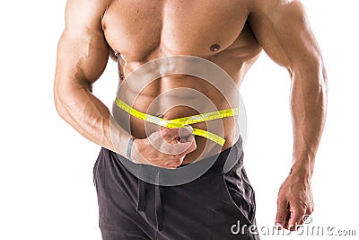Muscular bodybuilder man measuring belly with tape measure Stock Photo