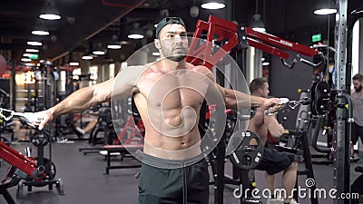 Muscular Bodybuilder Man with a Naked Torso Doing Exercises in Gym