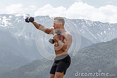 Muscular male athlete with arms raised doing lifting exercises dumbbells. Stock Photo