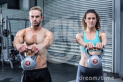 A muscular couple lifting kettlebells Stock Photo