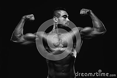 Muscular fitness burnet beard man is showing biceps on black background. BW Stock Photo