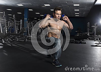 Muscular fitness man doing squats using fitness bag in modern fi Stock Photo