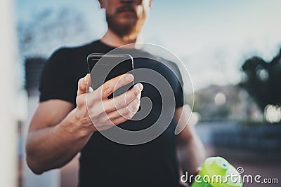 Muscular handsome athlete checking burned calories on smartphone application and smart watch after good workout session Stock Photo