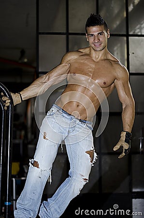 Muscular latino bodybuilder in jeans hanging from metal handle Stock Photo