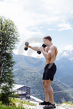 Muscular male athlete with arms raised doing lifting exercises dumbbells. Stock Photo