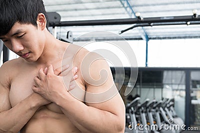 Muscular male having pain on shoulder in gym. young man injure Stock Photo