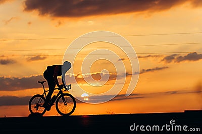 Muscular man biking on road during amazing sunset Stock Photo