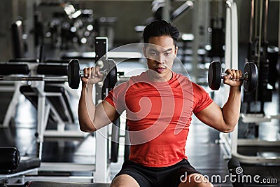 Muscular man exercise dumbbell in gym Stock Photo