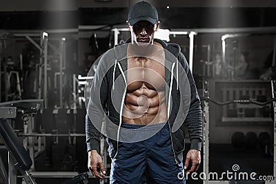 Muscular man with open jacket revealing chest and abs in gym, workout Stock Photo