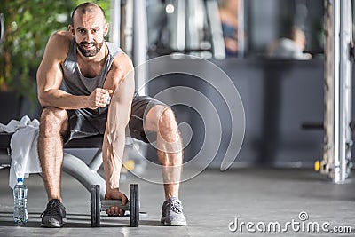 Muscular man practicing with dumbbells in fitness gym Stock Photo
