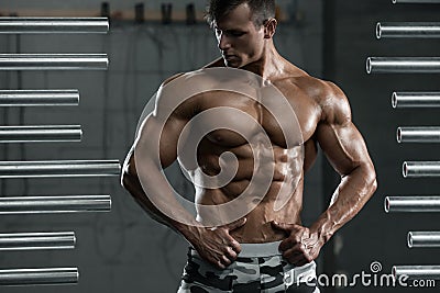 Muscular man showing muscles, posing in gym. Strong male naked torso abs, working out Stock Photo