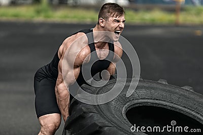 Muscular man working out flipping tire, outdoor. Strong male crossfit training Stock Photo