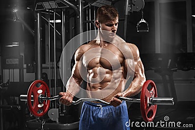 Muscular man working out in gym doing exercises with barbell at biceps, strong male naked torso abs Stock Photo