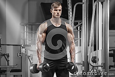 Muscular man working out in gym doing exercises, handsome strong male Stock Photo