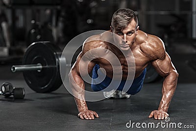 Muscular man working out in gym doing push-ups exercises, strong male naked torso abs Stock Photo