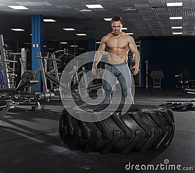 Muscular,Strong bodybuilder pushing tire in modern fitness cente Stock Photo