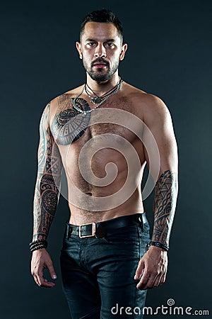 Muscular tattooed athlete look attractive. Sport and fashion concept. Handsome fit man posing wearing in jeans with Stock Photo