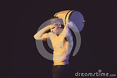 Muscular worker shirtless holding big blue barrel over his head. Stock Photo