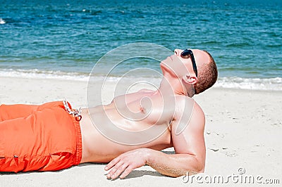 Muscular young athletic man lying on the beach Stock Photo