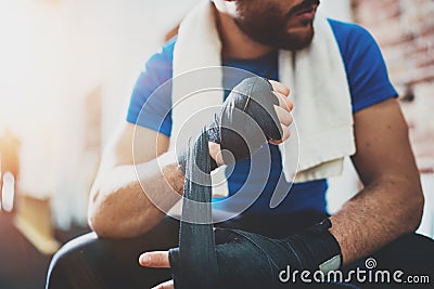 Muscular young boxer with black boxing bandages. Fists of fighter before the fight or training in sport gym. Blurred Stock Photo