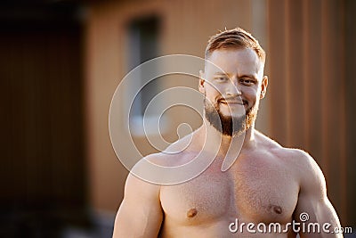 Muscular young European man without shirt outdoors in countryside near house. Stock Photo