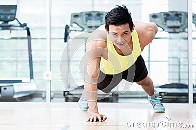 Muscular young man doing one armed pushups in gym Stock Photo