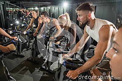 Muscular young men and women on cycling class at gym Stock Photo