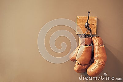 Museum of box sport. Box exhibition retro attributes. Boxing school. Vintage boxing gloves hang on hook wall background Editorial Stock Photo